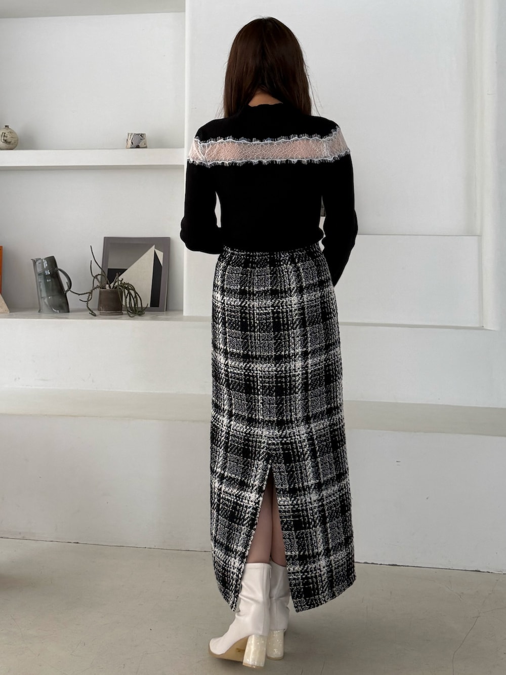 ブラック系のニット/セーター、ブラック系のスカート、ホワイト系のブーツを着用したレディースの秋コーディネートの3枚目の写真