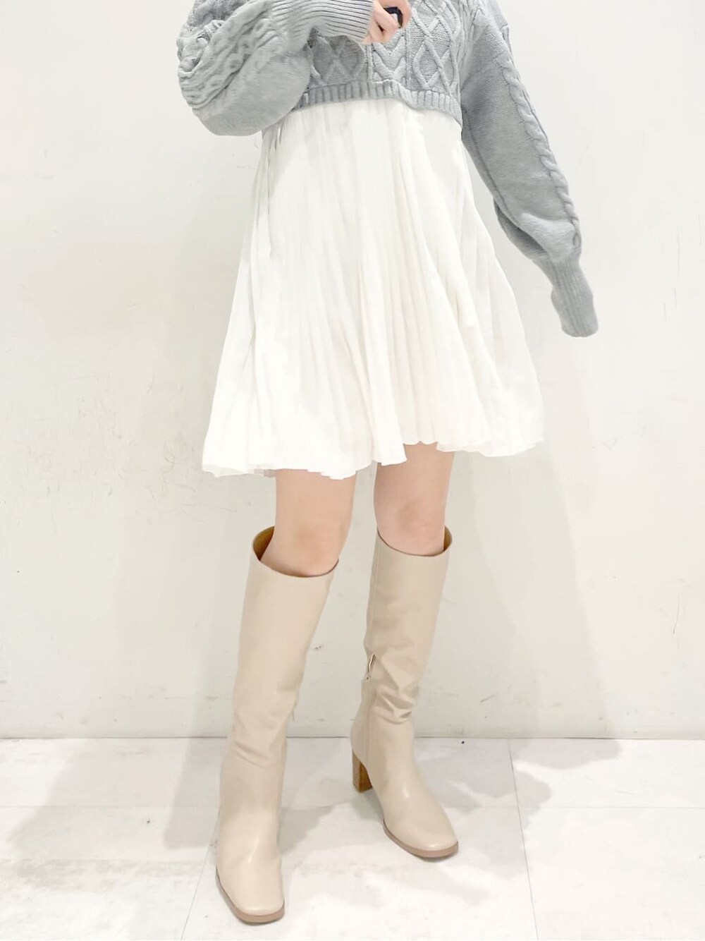 ブラウン系のブルゾン、ベージュ系のブーツ、グレー系のワンピースを着用したレディースの冬コーディネートの7枚目の写真