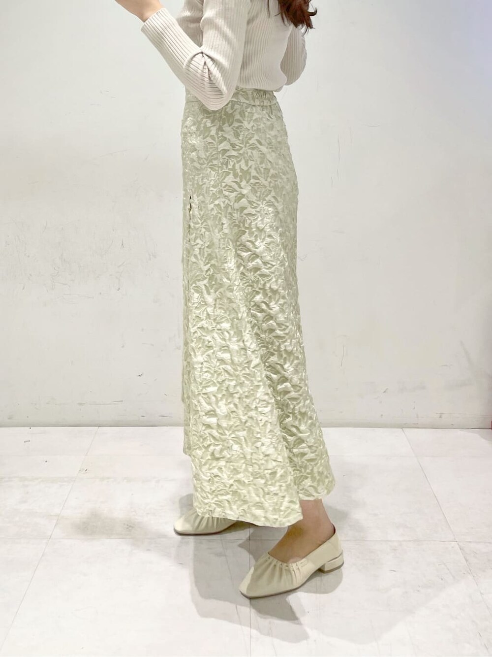 グリーン系のスカート、ホワイト系のパンプス、ベージュ系のニット/セーターを着用したレディースの冬コーディネートの6枚目の写真