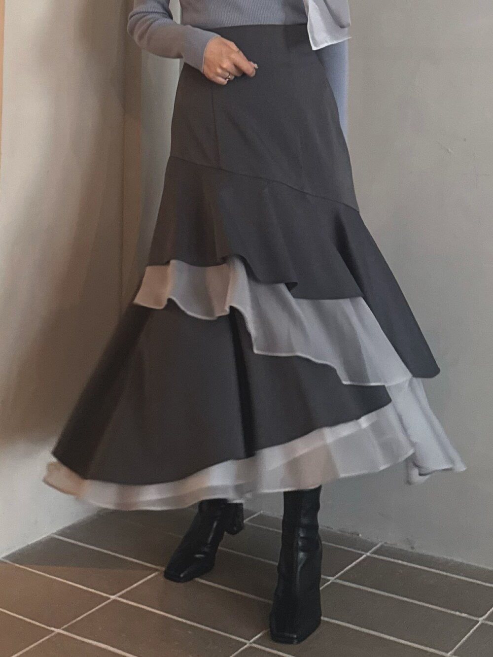 ブルー系のニット/セーター、グレー系のスカート、ブラック系のブーツを着用したレディースの秋コーディネートの6枚目の写真