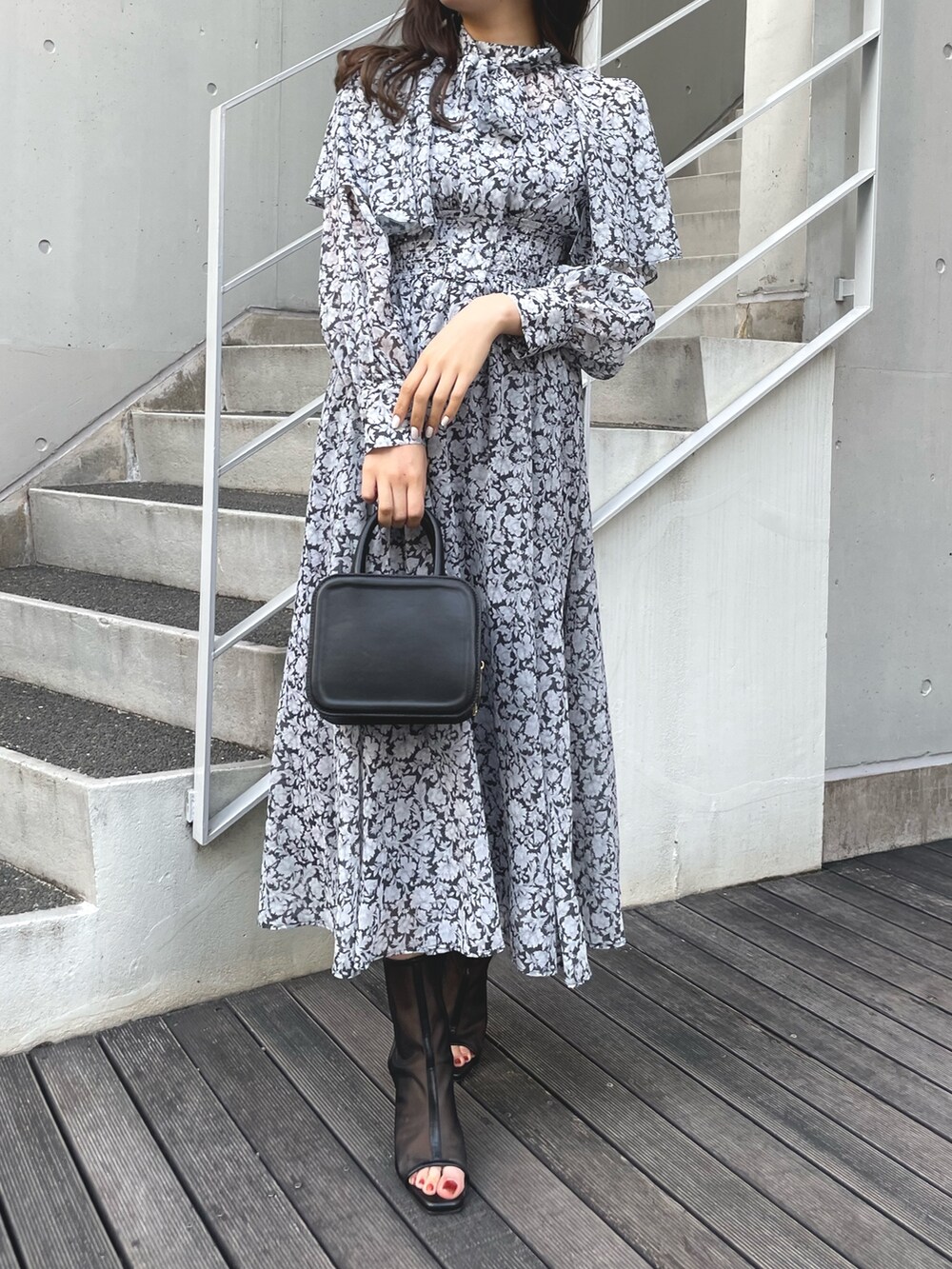 ブラック系のワンピース、ブラック系のハンドバッグ、ブラック系のブーツを着用したレディースの冬コーディネートの2枚目の写真