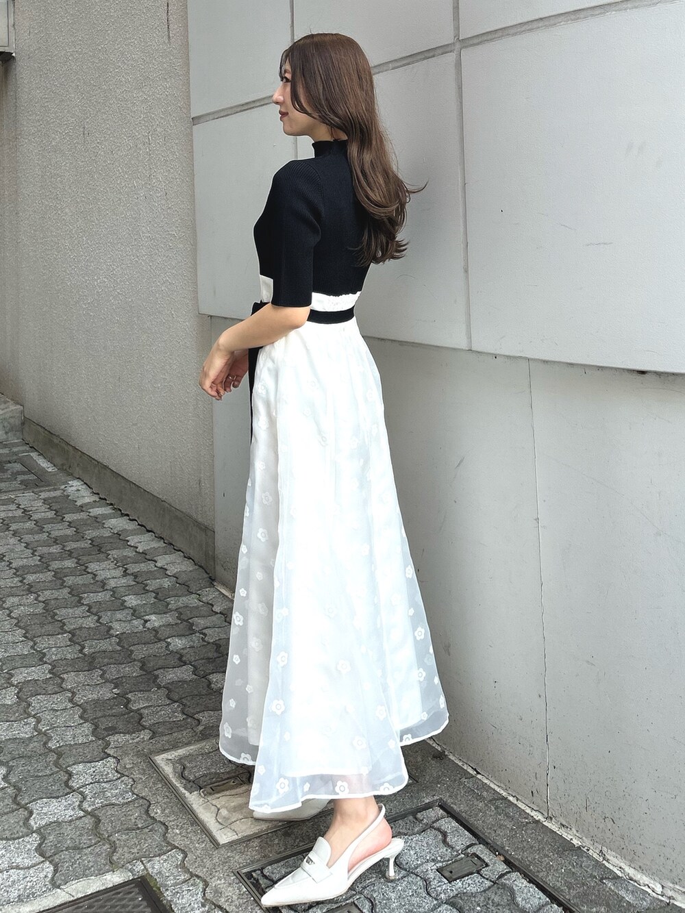 ブラック系のワンピース、ホワイト系のパンプス、パープル系のトレンチコートを着用したレディースの冬コーディネートの2枚目の写真