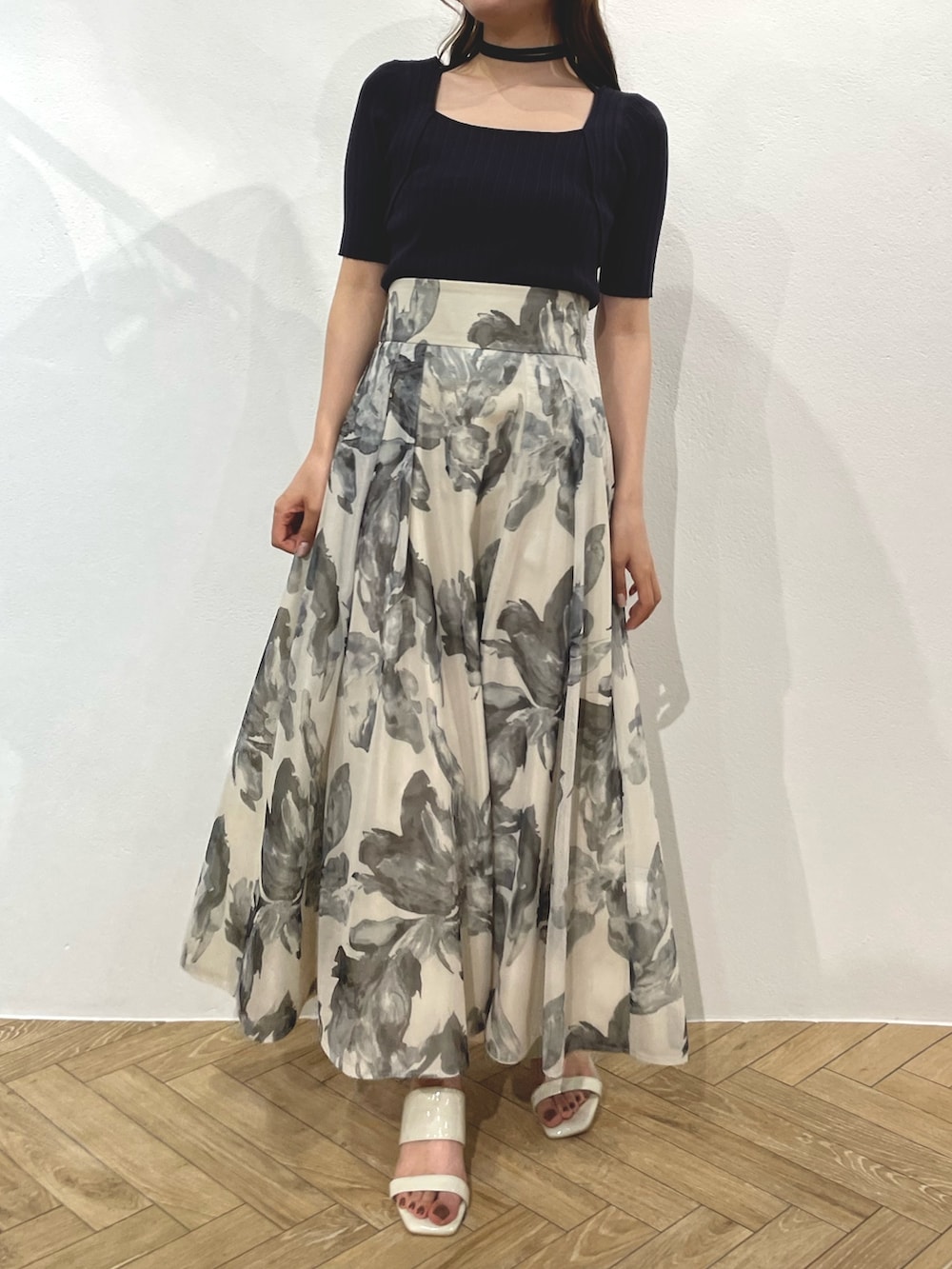 グレー系のニット/セーター、ホワイト系のスカート、ホワイト系のサンダルを着用したレディースの春コーディネートの2枚目の写真