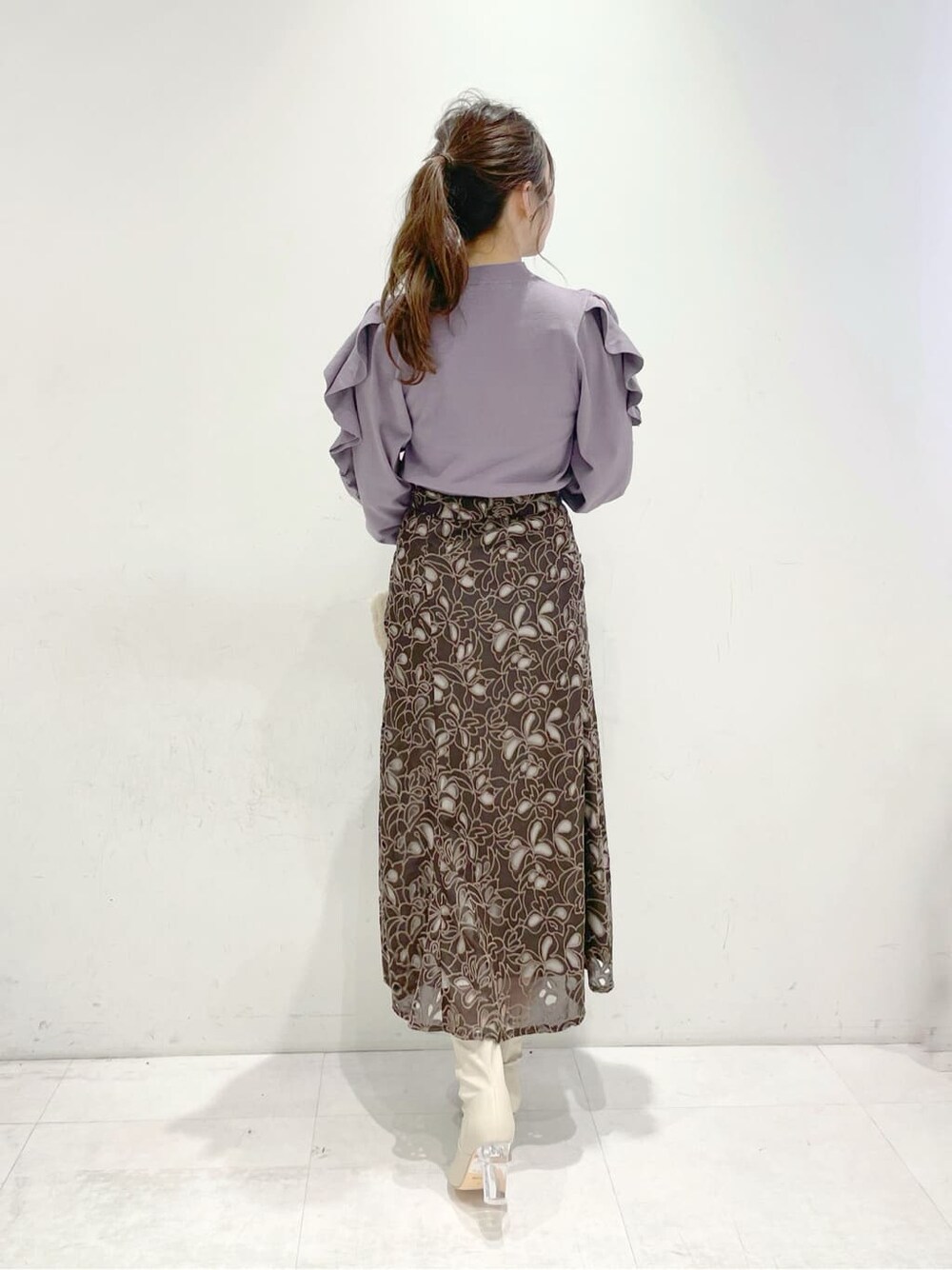 パープル系のニット/セーター、ベージュ系のハンドバッグ、ブラウン系のスカートを着用したレディースの冬コーディネートの3枚目の写真