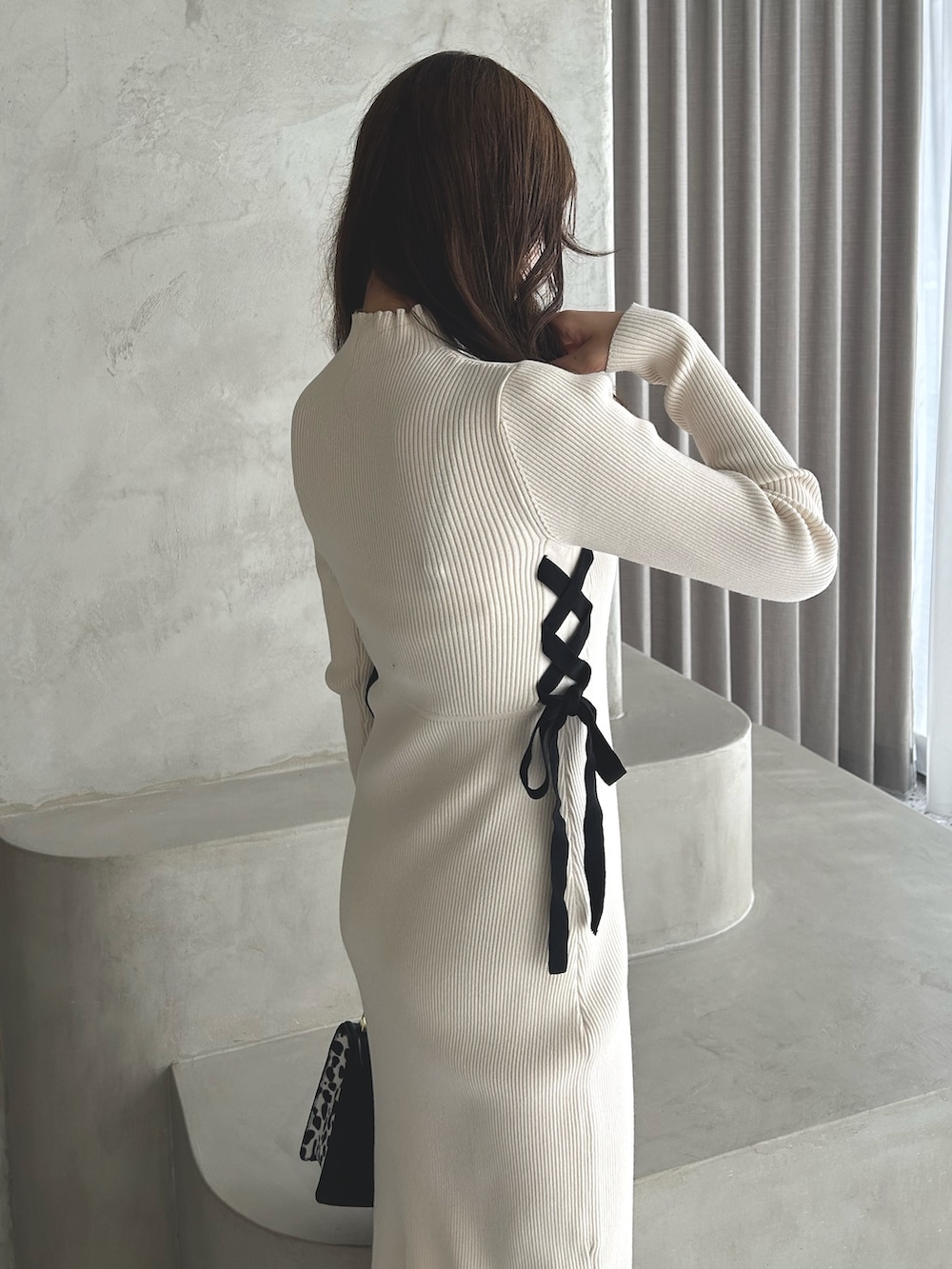 ホワイト系のワンピース、ブラック系のブーツ、ブラック系のハンドバッグを着用したレディースの冬コーディネートの3枚目の写真