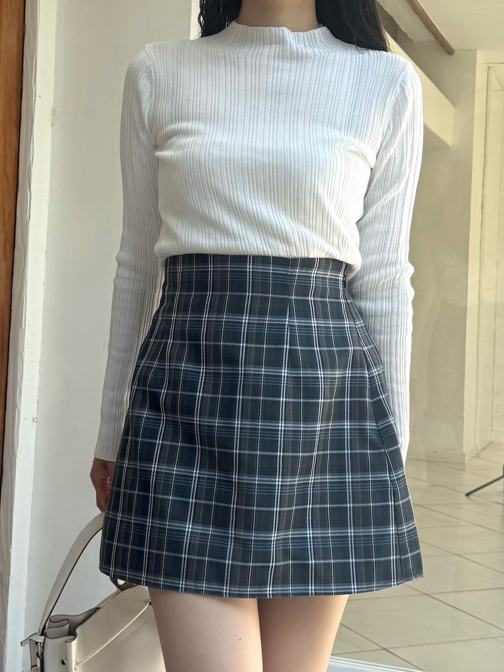 グリーン系のスカート、ホワイト系のニット/セーター、ホワイト系のショルダーバッグを着用したレディースの秋コーディネートの3枚目の写真