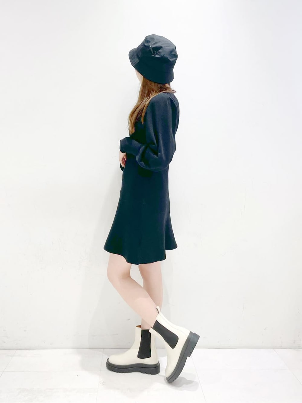 ホワイト系のブーツ、ブラック系のワンピース、ブラック系のハットを着用したレディースの冬コーディネートの2枚目の写真