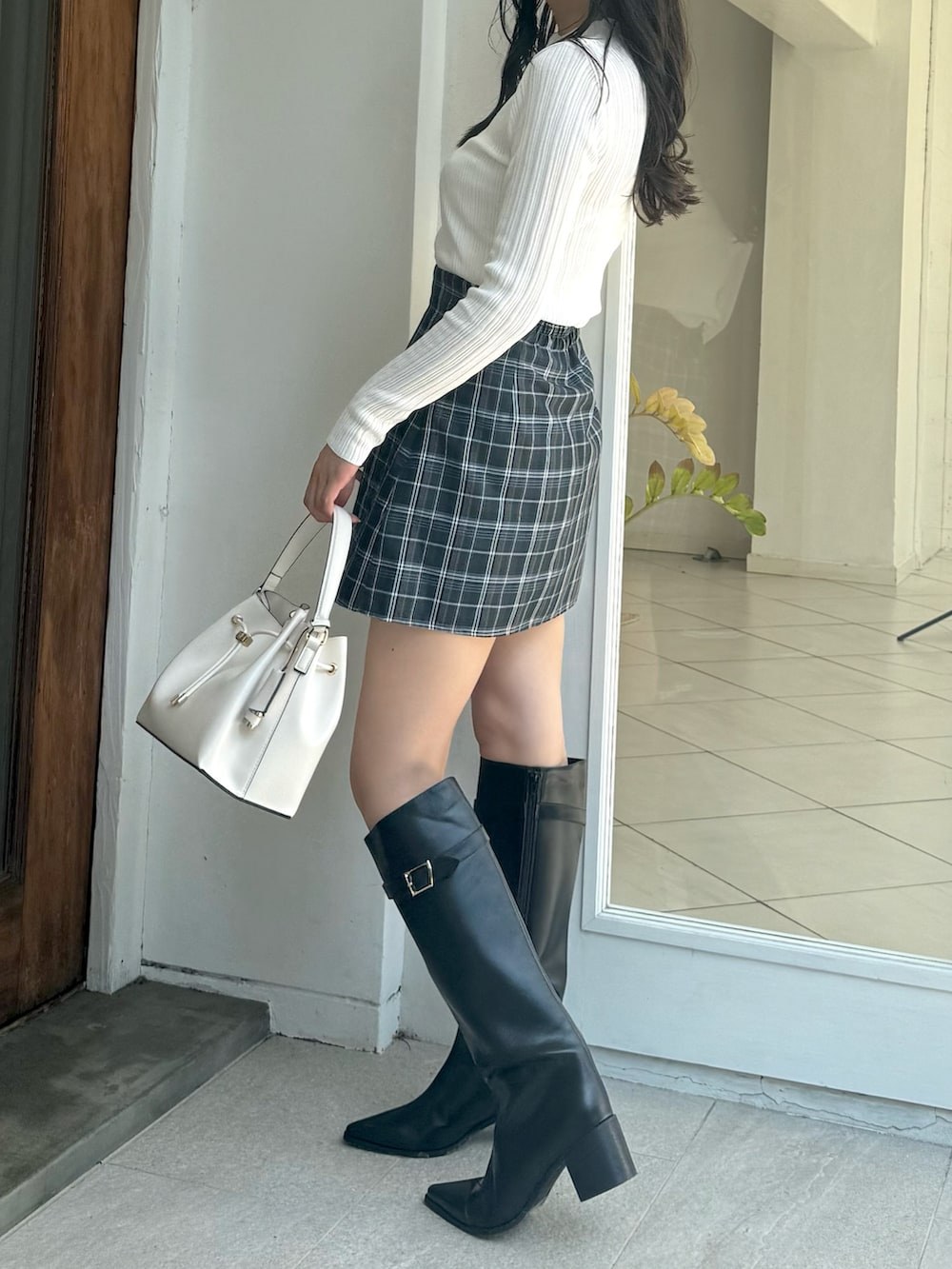 グリーン系のスカート、ホワイト系のニット/セーター、ホワイト系のショルダーバッグを着用したレディースの秋コーディネートの2枚目の写真