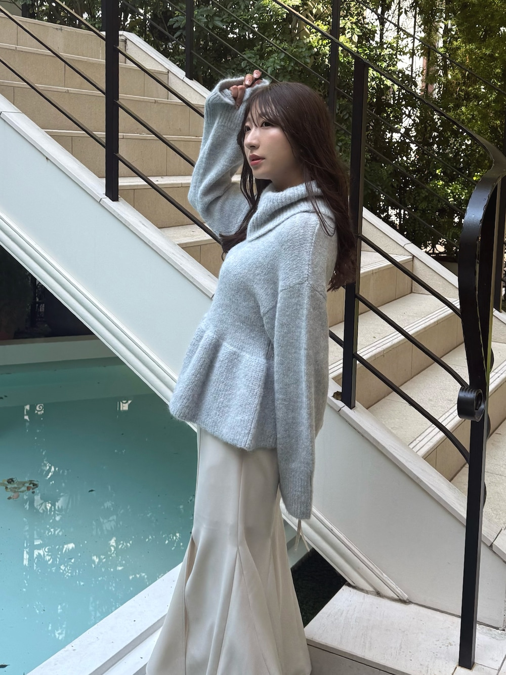 グレー系のニット/セーター、ホワイト系のスカート、ブラック系のブーツを着用したレディースの秋コーディネートの4枚目の写真