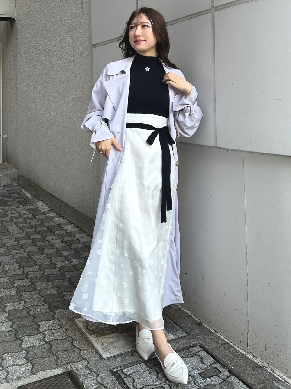 ブラック系のワンピース、ホワイト系のパンプス、パープル系のトレンチコートを着用したレディースの冬コーディネートの6枚目の写真