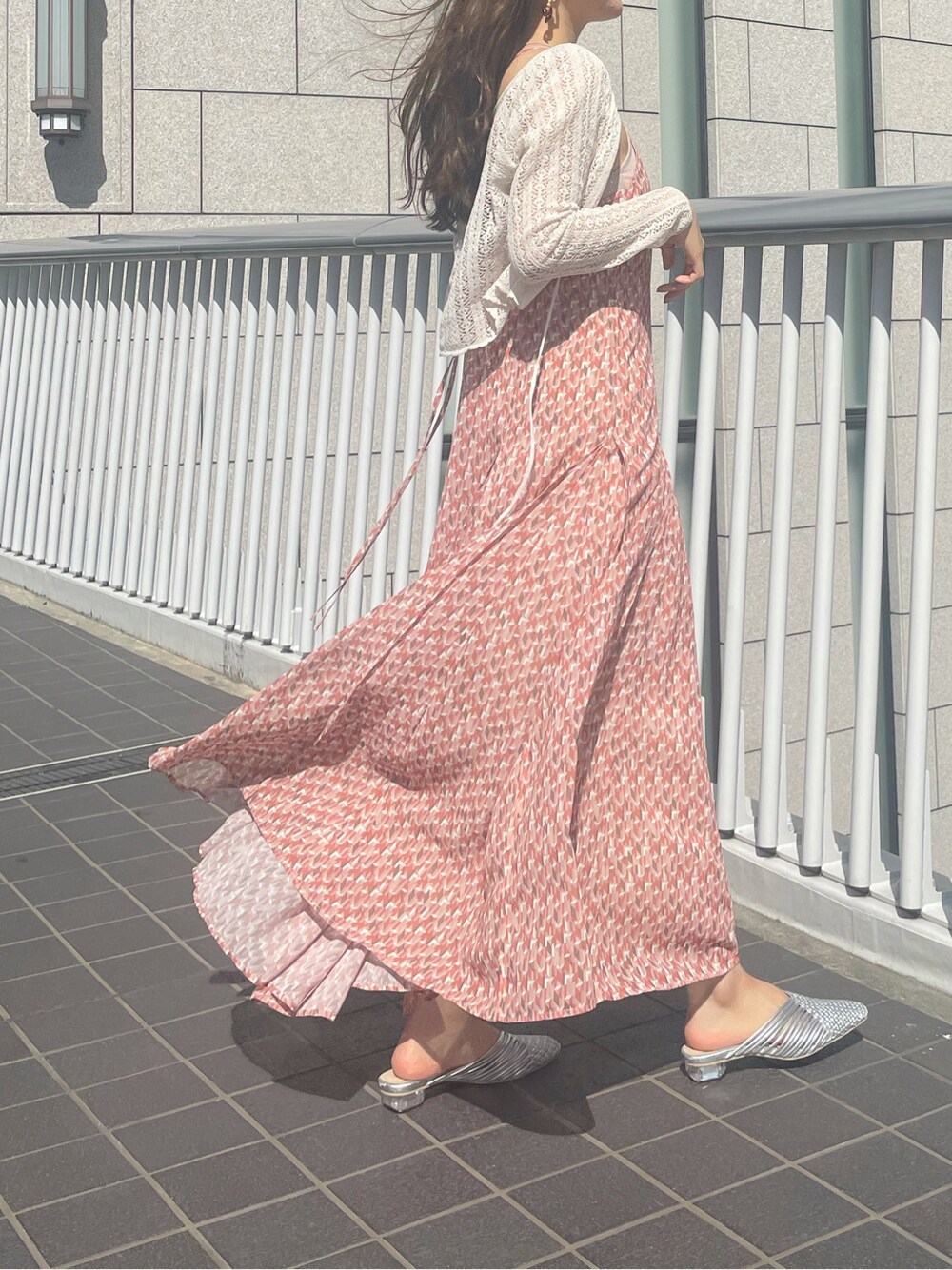 シルバー系のサンダル、オレンジ系のワンピース、ホワイト系のニット/セーターを着用したレディースの春コーディネートの2枚目の写真