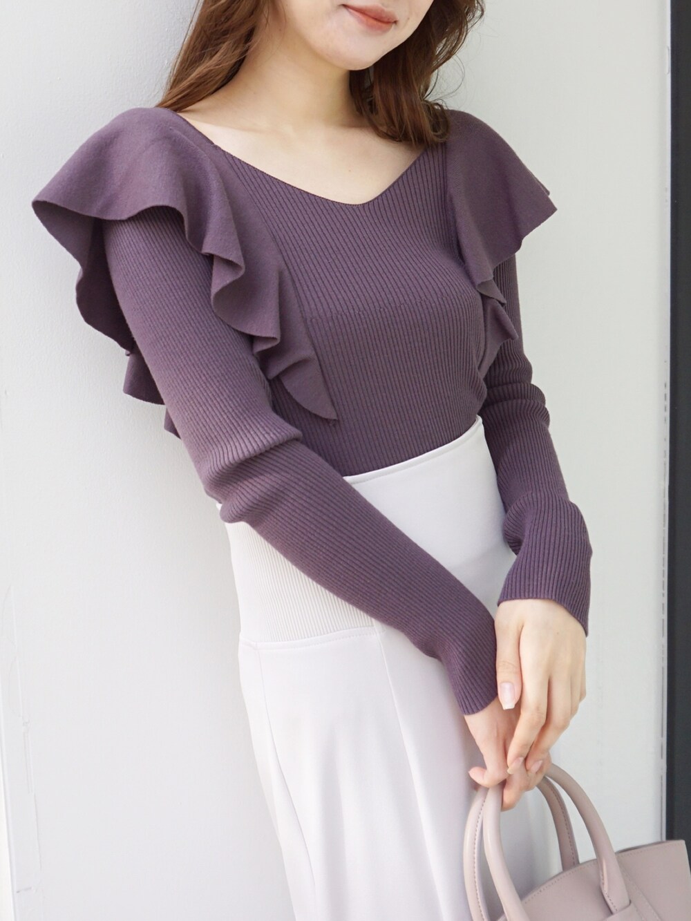 パープル系のニット/セーター、ホワイト系のスカート、ベージュ系のハンドバッグを着用したレディースの冬コーディネートの4枚目の写真