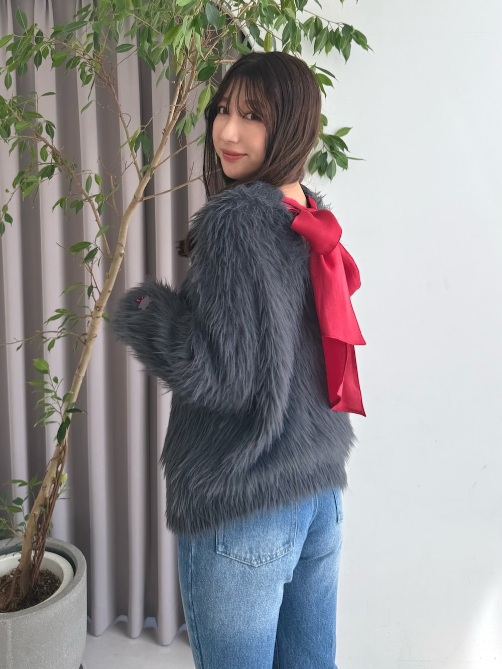 グレー系のニット/セーター、ブルー系のデニムパンツ、ブラウン系のブーツを着用したレディースの秋コーディネートの4枚目の写真