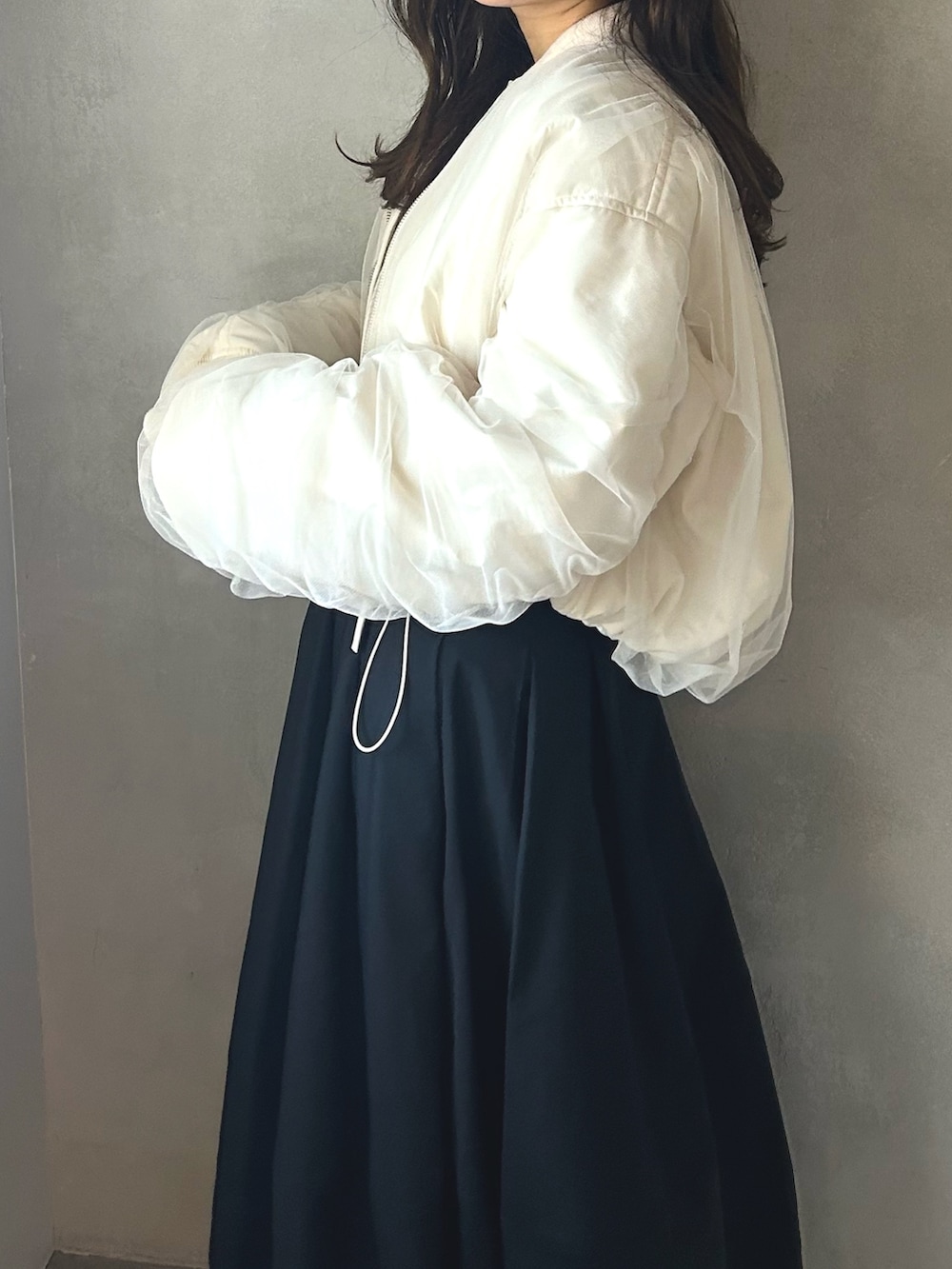 グレー系のニット/セーター、ホワイト系のMA-1、ブラック系のスカートを着用したレディースの春コーディネートの4枚目の写真