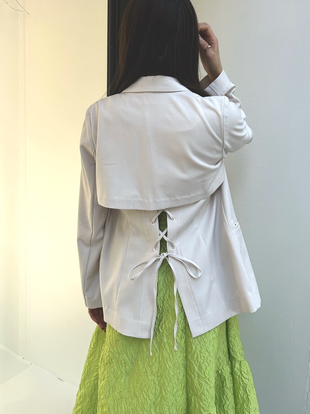 ホワイト系のニット/セーター、ホワイト系のテーラードジャケット、グリーン系のスカートを着用したレディースの春コーディネートの6枚目の写真