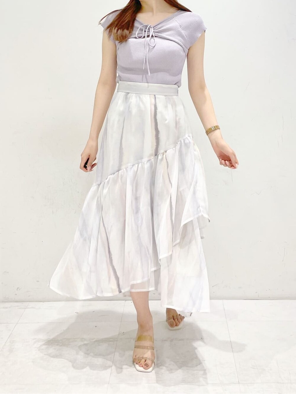 ピンク系のスカート、ベージュ系のサンダル、パープル系のニット/セーターを着用したレディースの春コーディネートの2枚目の写真