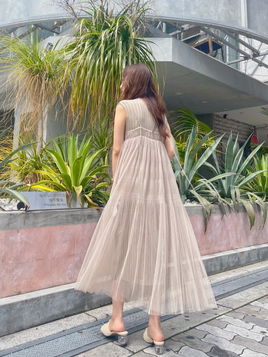 ベージュ系のワンピース、ホワイト系のサンダル、ゴールド系のイヤリングを着用したレディースの春コーディネートの2枚目の写真