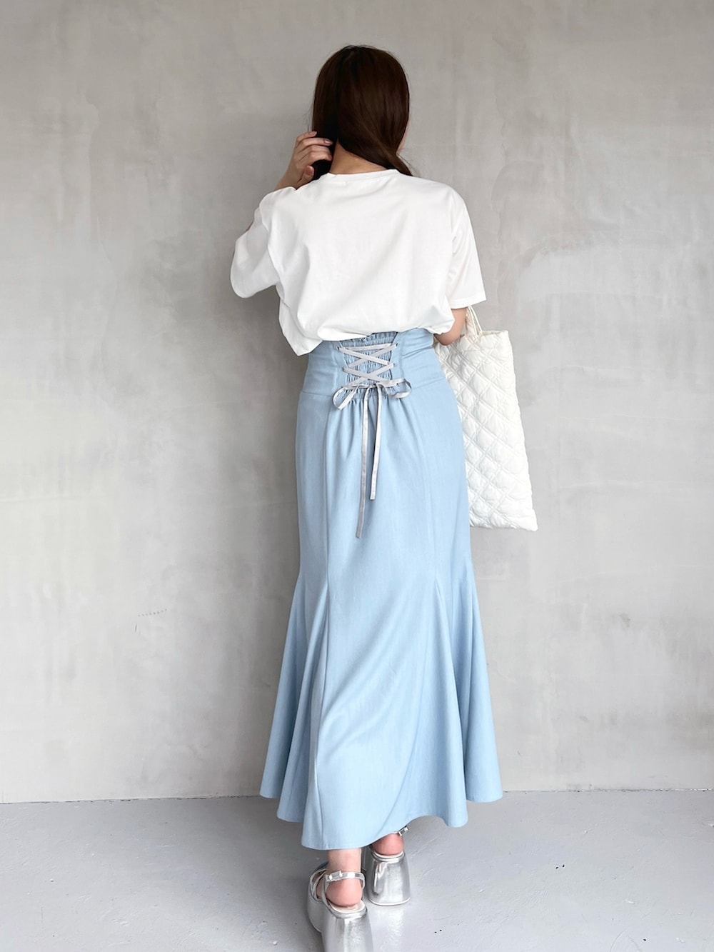 ブルー系のスカート、シルバー系のサンダル、ホワイト系のハンドバッグを着用したレディースの夏コーディネートの2枚目の写真