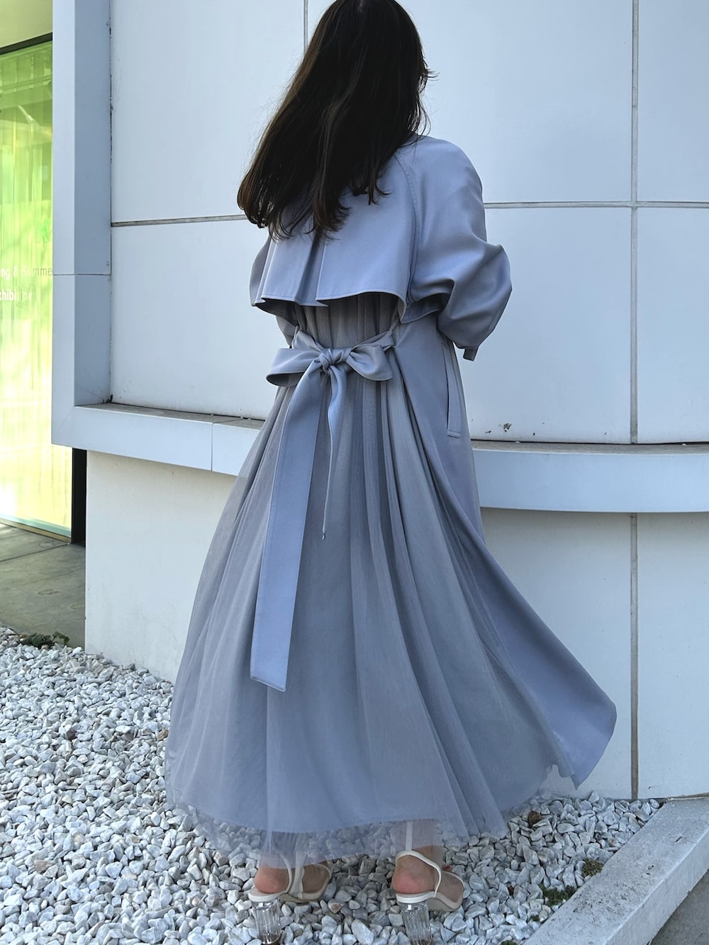 ブルー系のトレンチコート、ブラック系のワンピース、ホワイト系のブーツを着用したレディースの冬コーディネートの4枚目の写真