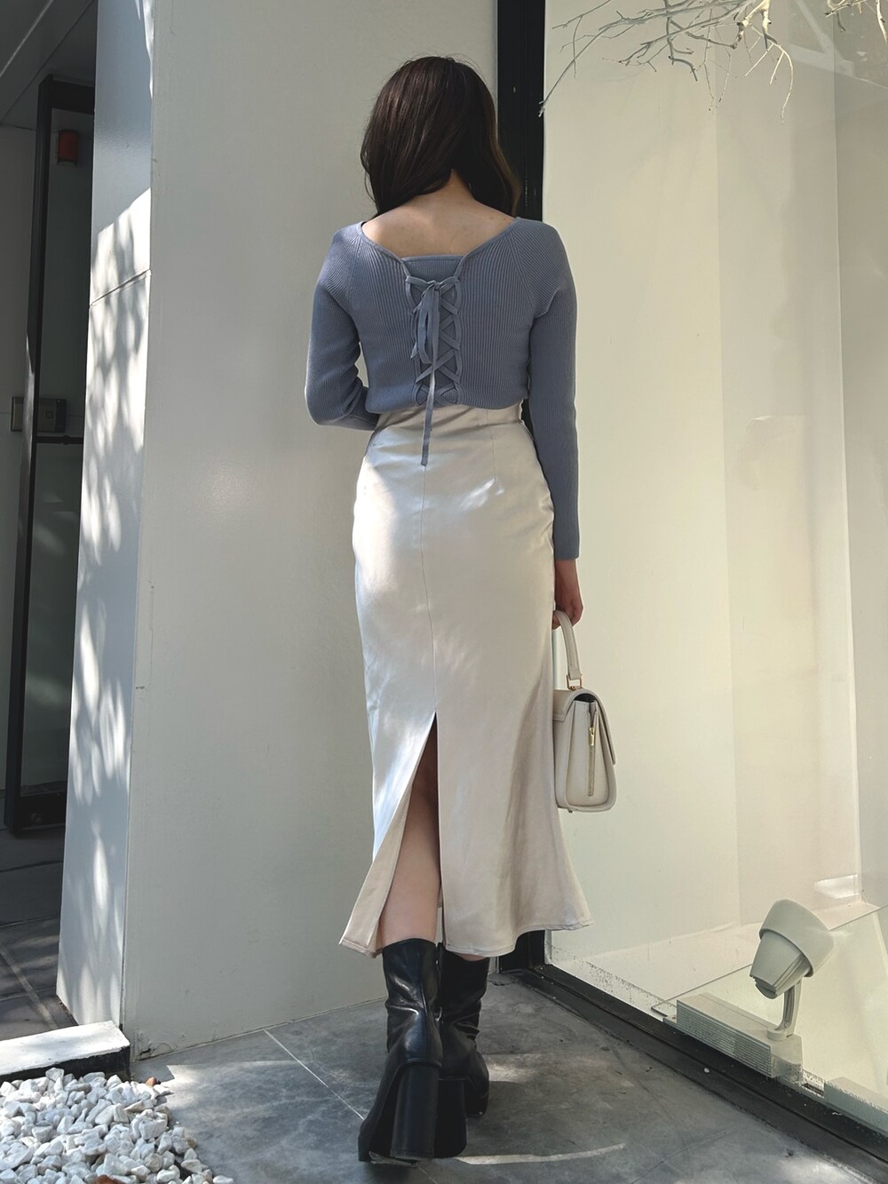 ブルー系のニット/セーター、ホワイト系のスカート、ブラック系のブーツを着用したレディースの秋コーディネートの4枚目の写真