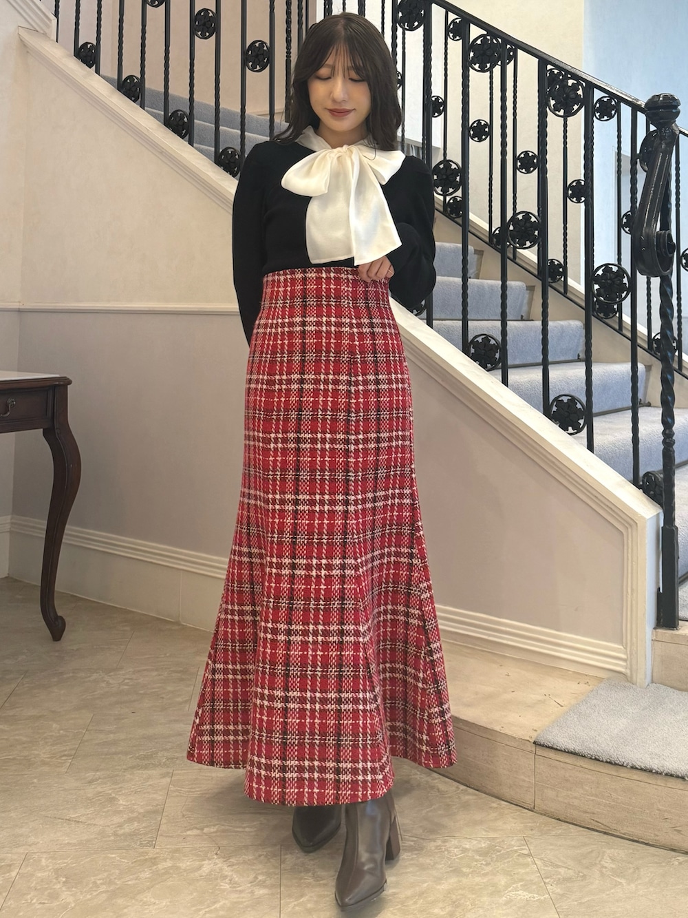 ブラック系のニット/セーター、レッド系のスカートを着用したレディースの秋コーディネートの2枚目の写真