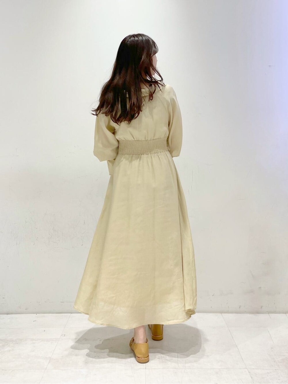 イエロー系のワンピース、ブラウン系のパンプスを着用したレディースの冬コーディネートの2枚目の写真