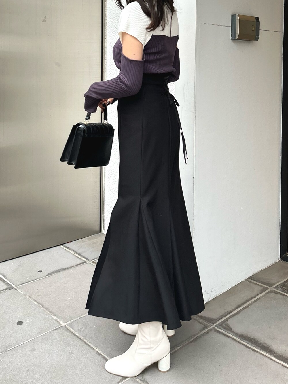 グレー系のニット/セーター、ブラック系のスカート、ブラック系のショルダーバッグを着用したレディースの冬コーディネートの4枚目の写真