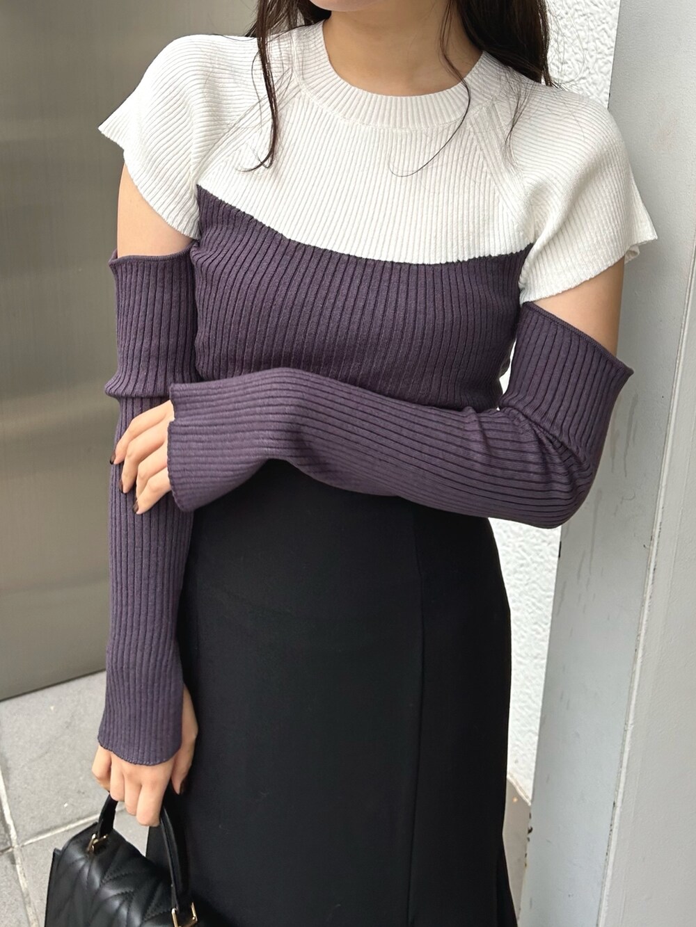 グレー系のニット/セーター、ブラック系のスカート、ブラック系のショルダーバッグを着用したレディースの冬コーディネートの6枚目の写真