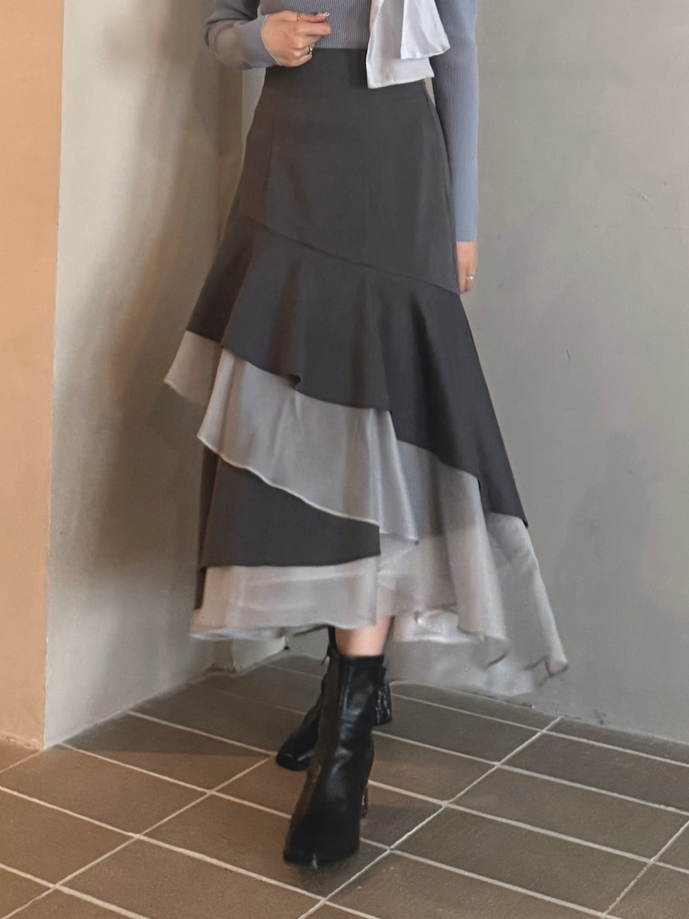 ブルー系のニット/セーター、グレー系のスカート、ブラック系のブーツを着用したレディースの秋コーディネートの5枚目の写真