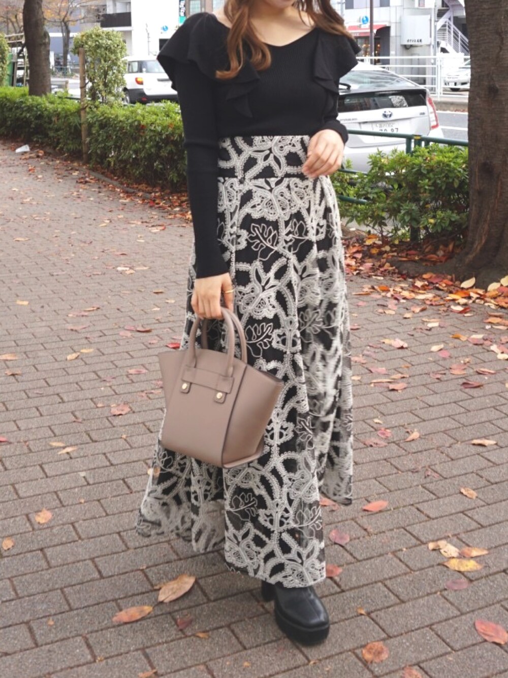 ブラック系のブーツ、ベージュ系のハンドバッグ、ブラック系のスカートを着用したレディースの冬コーディネートの5枚目の写真