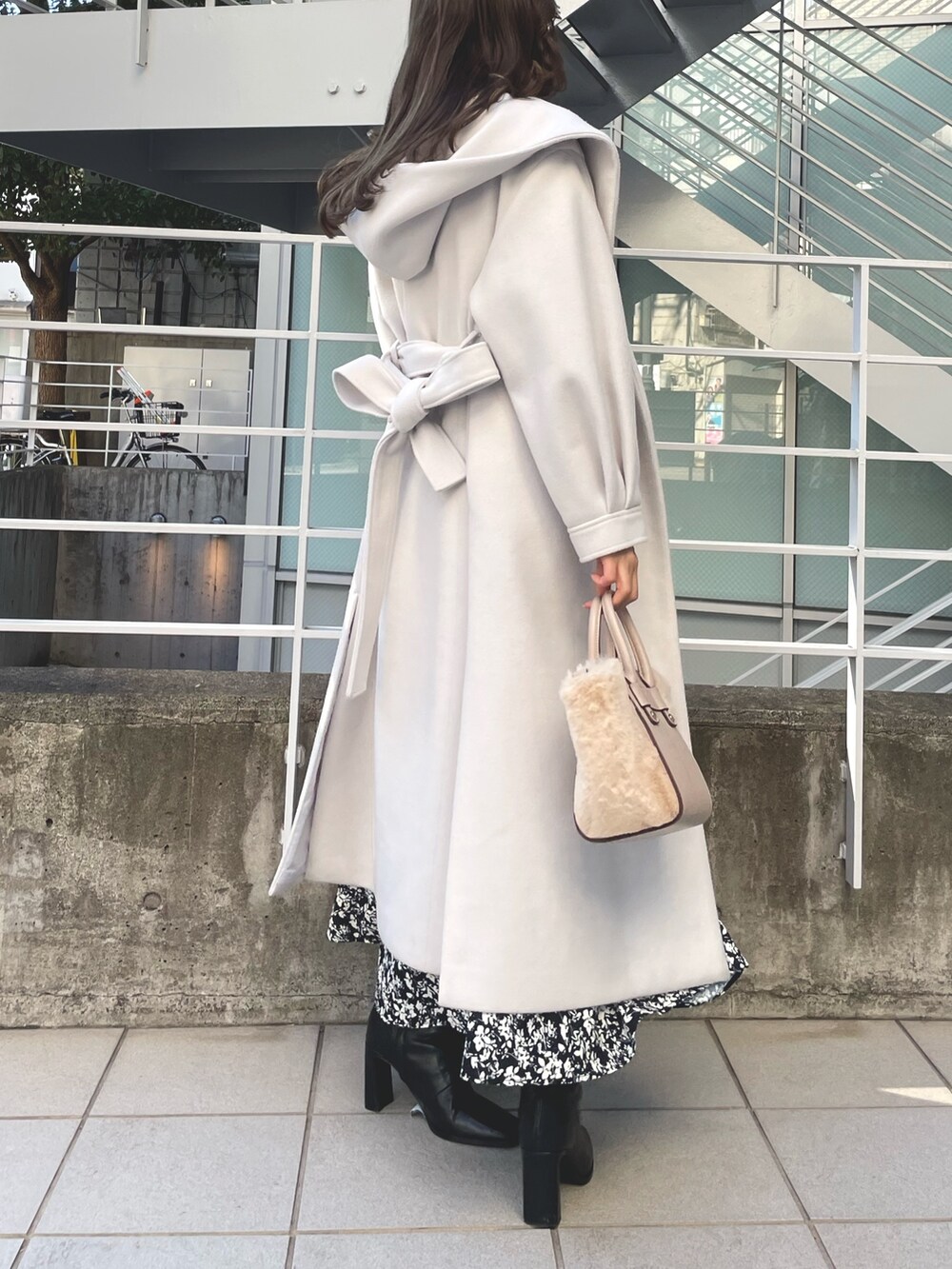 ホワイト系のチェスターコート、ブラック系のワンピース、ブラック系のブーツを着用したレディースの冬コーディネートの3枚目の写真