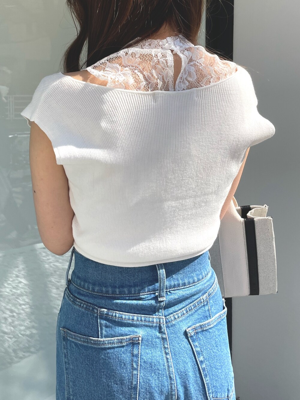 ブルー系のデニムパンツ、ホワイト系のハンドバッグ、パープル系のサンダルを着用したレディースの春コーディネートの4枚目の写真