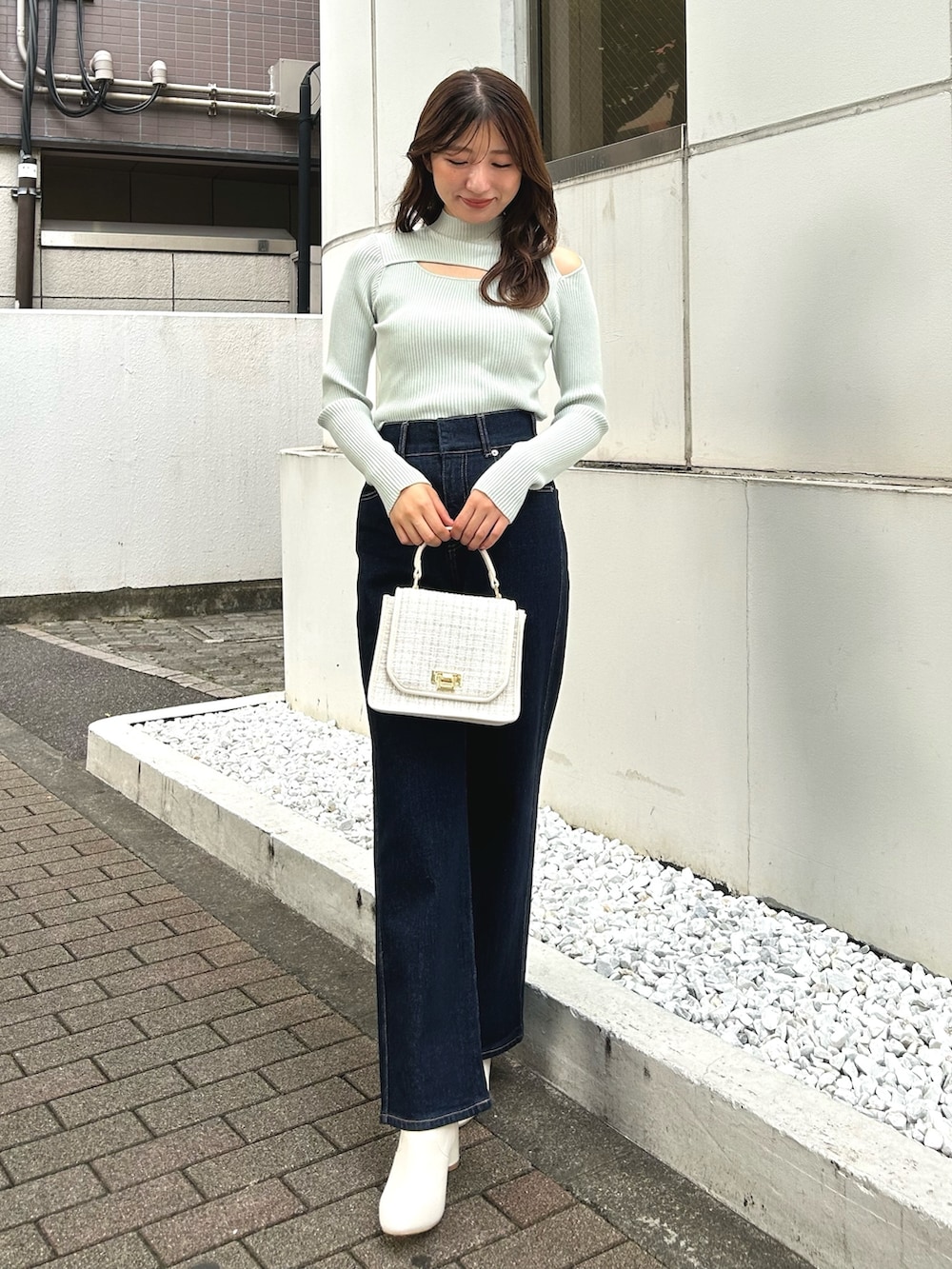 グリーン系のニット/セーター、ブルー系のデニムパンツ、ホワイト系のショルダーバッグを着用したレディースの秋コーディネートの3枚目の写真