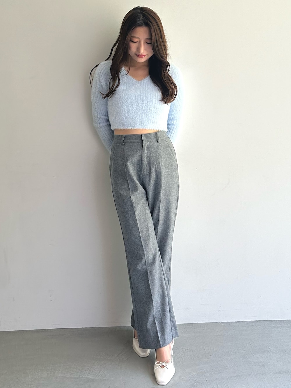 ブルー系のニット/セーター、グレー系のその他パンツ、ホワイト系のハンドバッグを着用したレディースの秋コーディネートの2枚目の写真