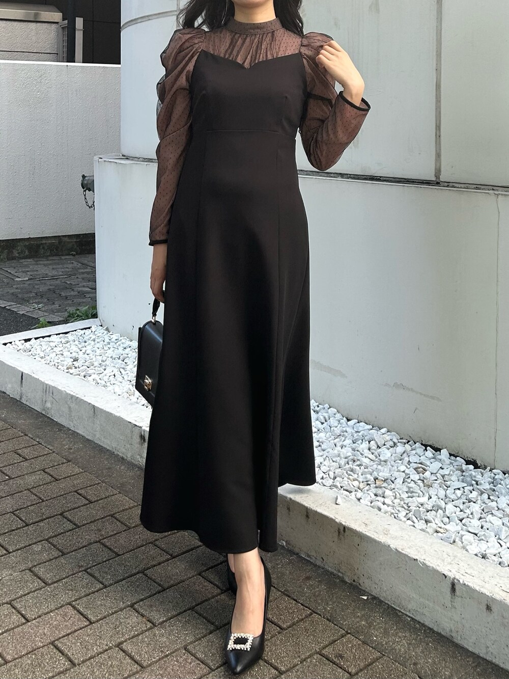 ブラック系のハンドバッグ、ブラック系のパンプス、ブラック系のワンピースを着用したレディースの秋コーディネートの3枚目の写真