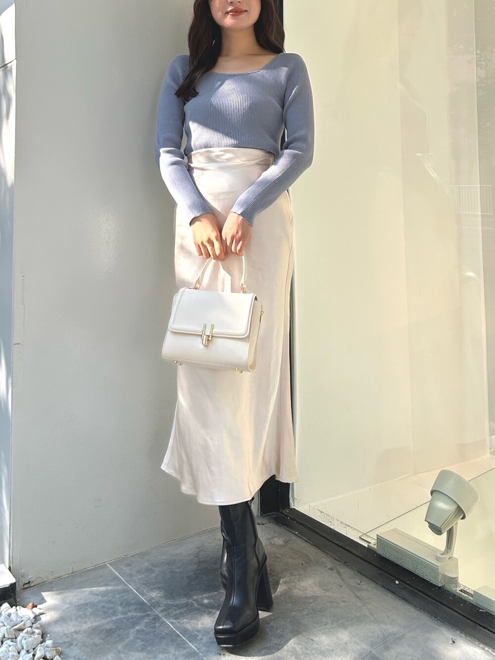 ブルー系のニット/セーター、ホワイト系のスカート、ブラック系のブーツを着用したレディースの秋コーディネートの3枚目の写真