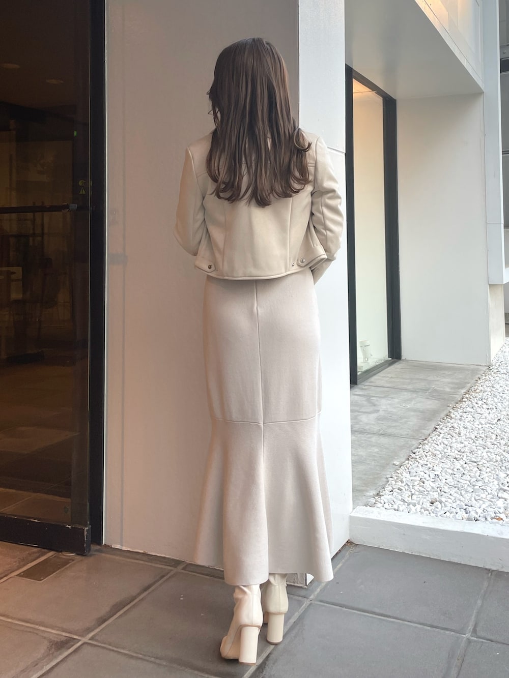 ホワイト系のワンピース、ベージュ系のライダースジャケットを着用したレディースの冬コーディネートの2枚目の写真