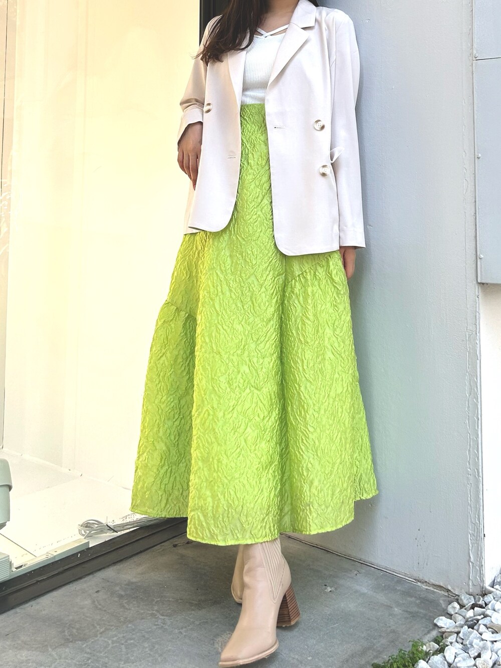 ホワイト系のニット/セーター、ホワイト系のテーラードジャケット、グリーン系のスカートを着用したレディースの春コーディネートの3枚目の写真