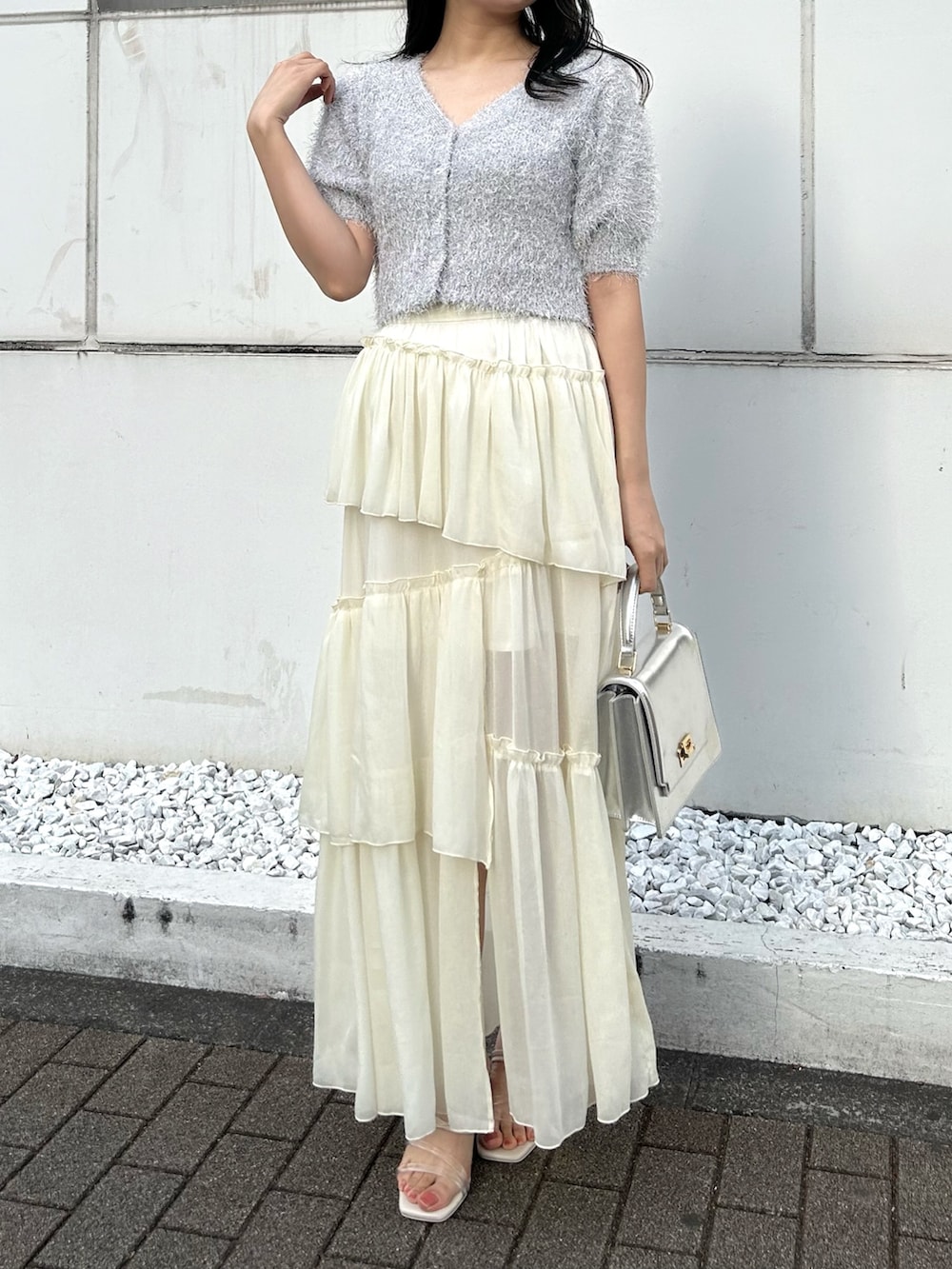 ホワイト系のカーディガン/ボレロ、シルバー系のハンドバッグ、ホワイト系のスカートを着用したレディースの冬コーディネートの2枚目の写真