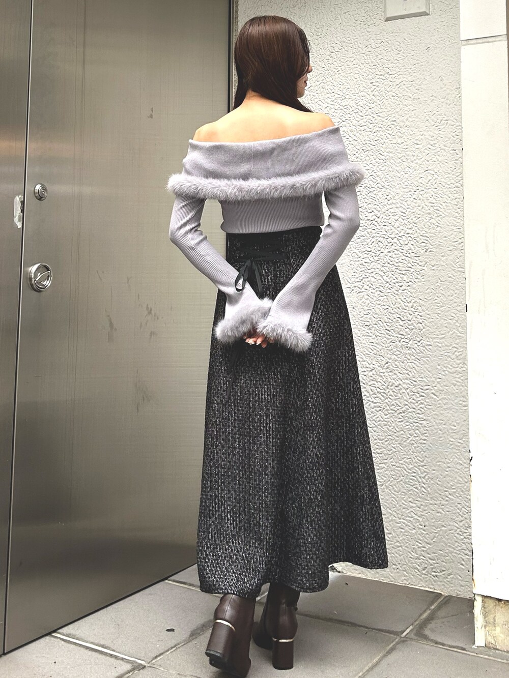 グレー系のニット/セーター、ブラック系のスカート、ブラウン系のブーツを着用したレディースの冬コーディネートの2枚目の写真