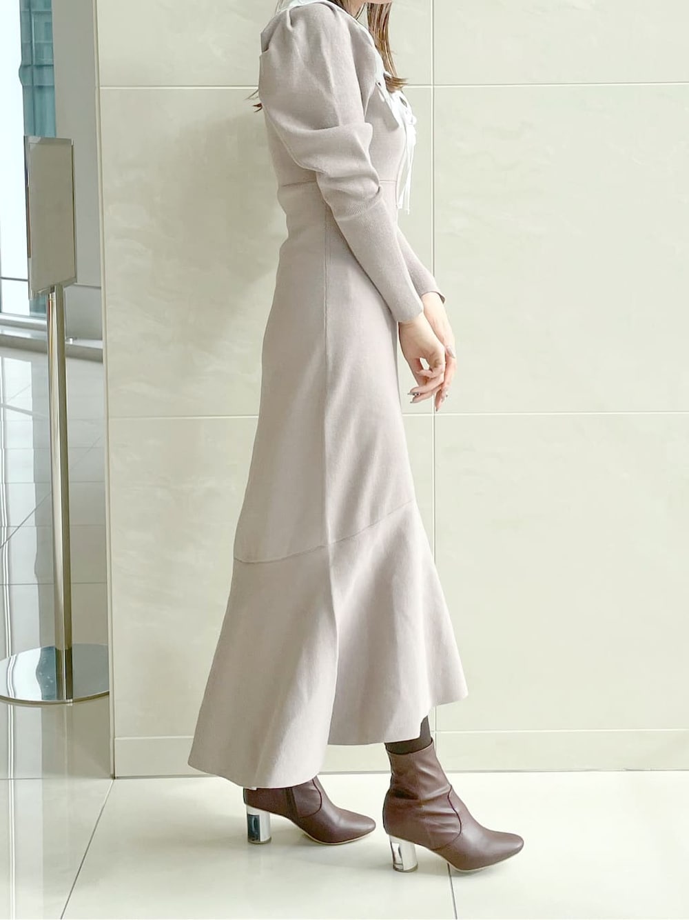 ベージュ系のワンピースを着用したレディースの冬コーディネートの2枚目の写真