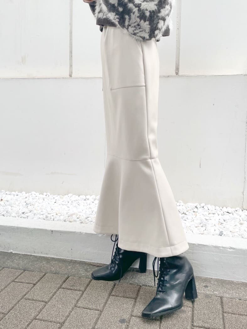 ブラウン系のニット/セーター、ブラック系のブーツ、ホワイト系のスカートを着用したレディースの秋コーディネートの5枚目の写真