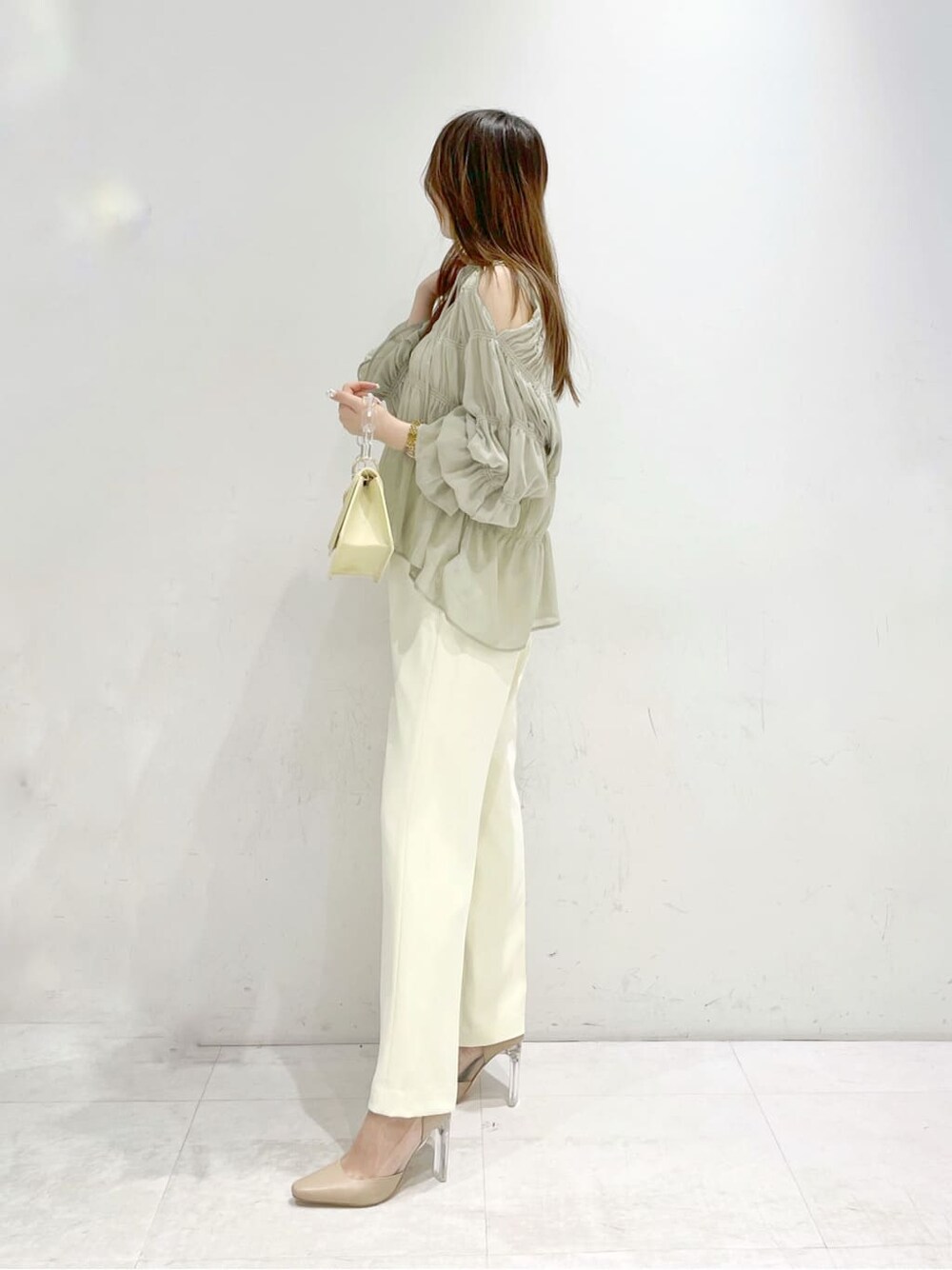 イエロー系のシャツ/ブラウス、ベージュ系のパンプス、イエロー系のショルダーバッグを着用したレディースの冬コーディネートの2枚目の写真