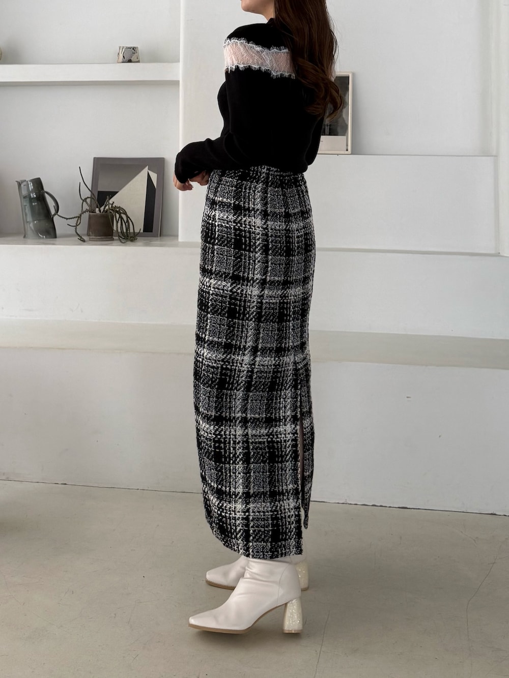 ブラック系のニット/セーター、ブラック系のスカート、ホワイト系のブーツを着用したレディースの秋コーディネートの2枚目の写真