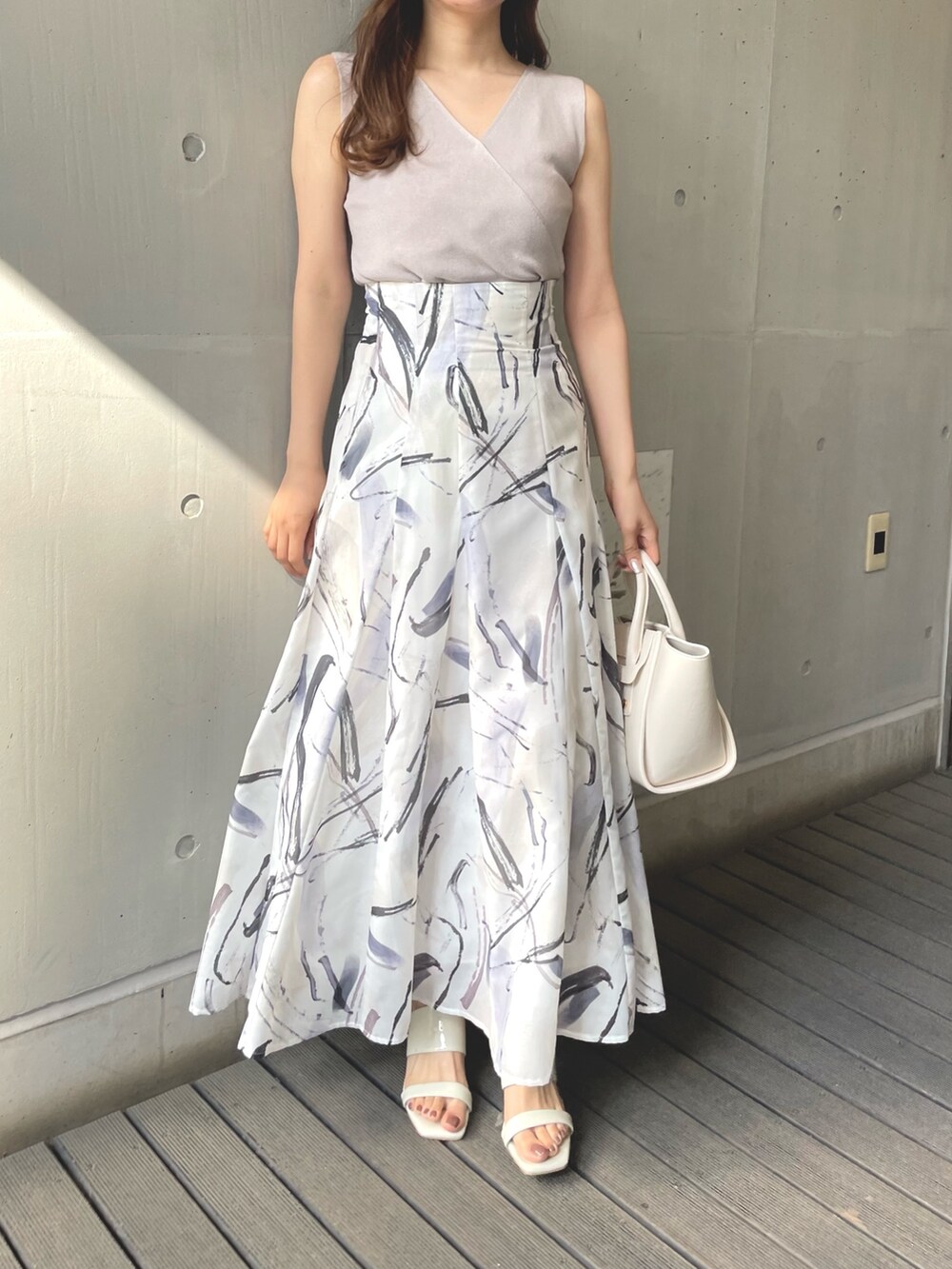 ピンク系のニット/セーター、グレー系のスカート、ホワイト系のトートバッグを着用したレディースの春コーディネートの2枚目の写真