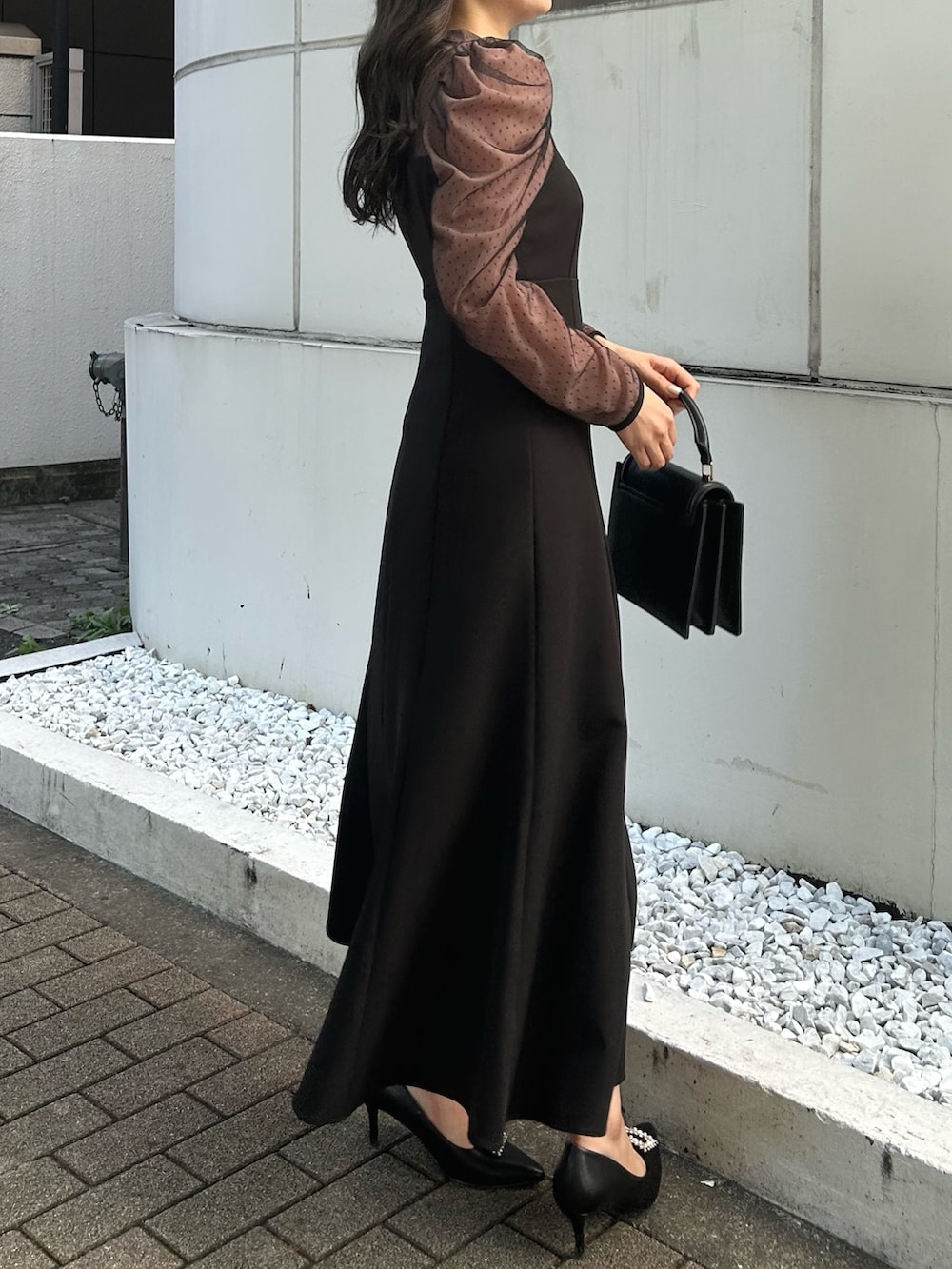 ブラック系のハンドバッグ、ブラック系のパンプス、ブラック系のワンピースを着用したレディースの秋コーディネートの5枚目の写真