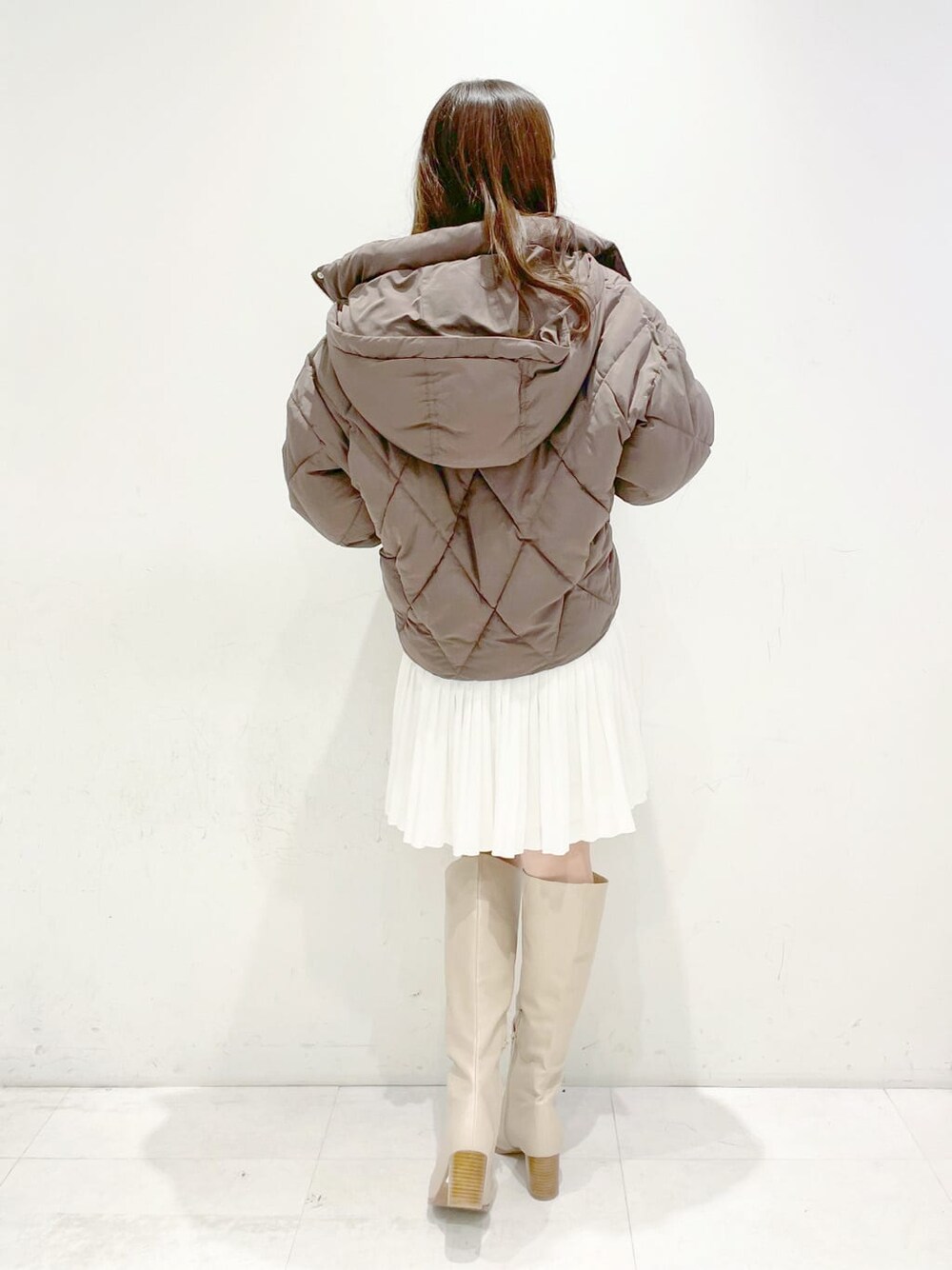 ブラウン系のブルゾン、ベージュ系のブーツ、グレー系のワンピースを着用したレディースの冬コーディネートの2枚目の写真