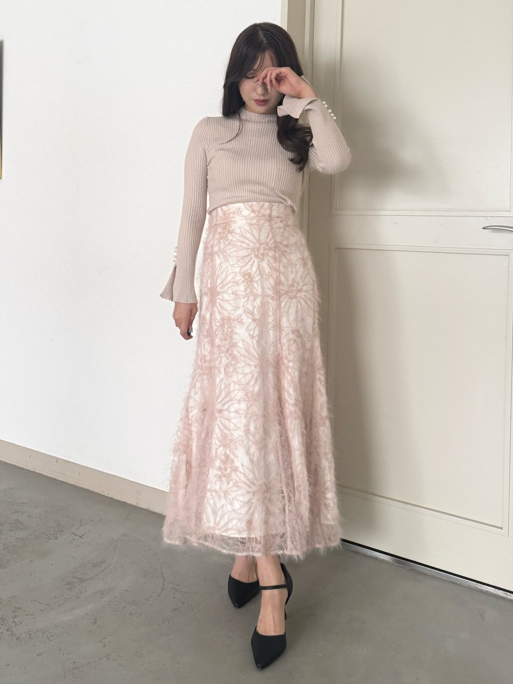 ベージュ系のニット/セーター、ピンク系のスカート、ブラック系のパンプスを着用したレディースの秋コーディネートの2枚目の写真