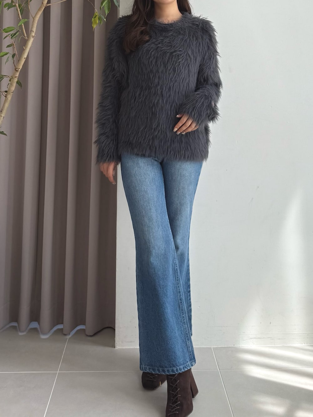 グレー系のニット/セーター、ブルー系のデニムパンツ、ブラウン系のブーツを着用したレディースの秋コーディネートの2枚目の写真