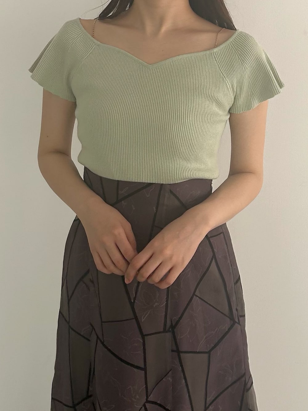 グリーン系のニット/セーター、ブラウン系のスカート、グレー系のパンプスを着用したレディースの夏コーディネートの4枚目の写真